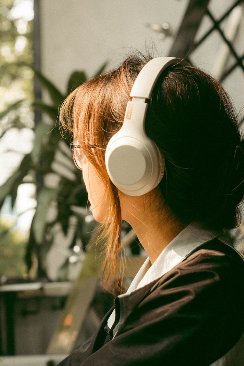 a woman wearing headphones sitting in front of a plant