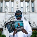 man in white thobe holding newspaper