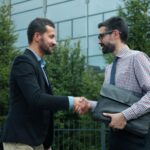 Two businessmen shaking hands outside modern building