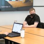 a group of people sitting around a table with a laptop