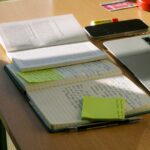 Notebook and laptop sit on a work desk.