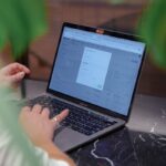a woman sitting at a table using a laptop computer
