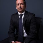 Man in a suit sitting with hands clasped